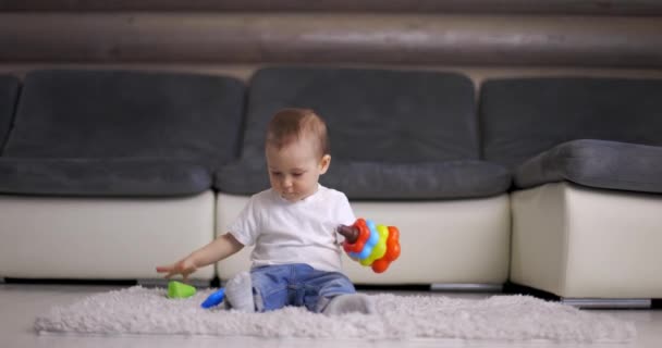 Lindo niño pequeño jugando con colorido juguete pirámide en casa — Vídeo de stock