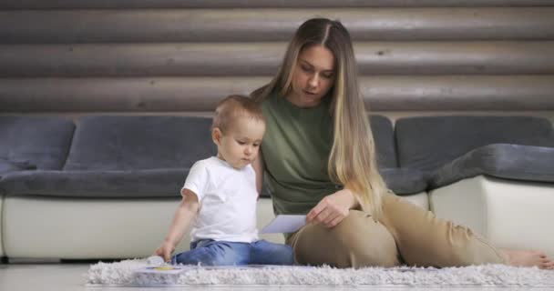 Heureux jeune mère et bébé fils jouant avec la carte alphabet sur le sol chaud à la maison, l'éducation précoce à la maison. — Video