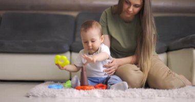 Mutlu anne ve çocuk evde piramitlerle birlikte oynuyorlar. Anne ve bebek birlikte oynayıp eğleniyorlar..