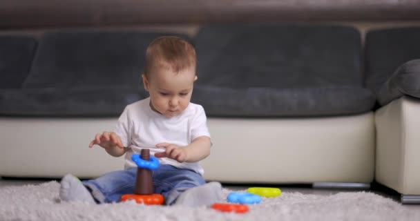 Lindo niño pequeño jugando con colorido juguete pirámide en casa — Vídeo de stock