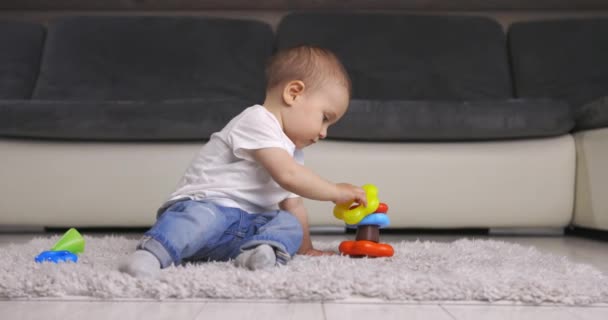 Lindo niño pequeño jugando con colorido juguete pirámide en casa — Vídeo de stock