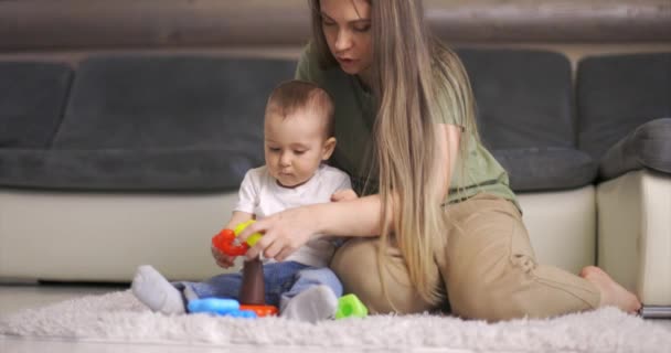 Felice giovane madre e bambino ragazzo giocare insieme con piramide al chiuso a casa. Mamma e bambino bambino giocare e divertirsi insieme. — Video Stock