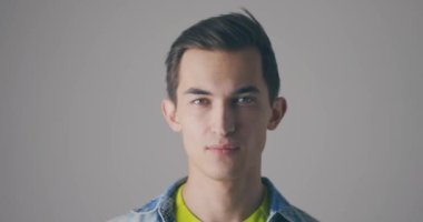 Genç yakışıklı beyaz adam yüz maskesi takıyor. Gri arkaplanda yakınlaştırma portresi. COVID-19 salgınına karşı solunum cihazıyla koruma