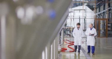 Bira fabrikasında çalışan iki Kafkasyalı adam. Bir erkek bira imalatçısı ölçümleri tablet kullanarak kontrol ediyor..