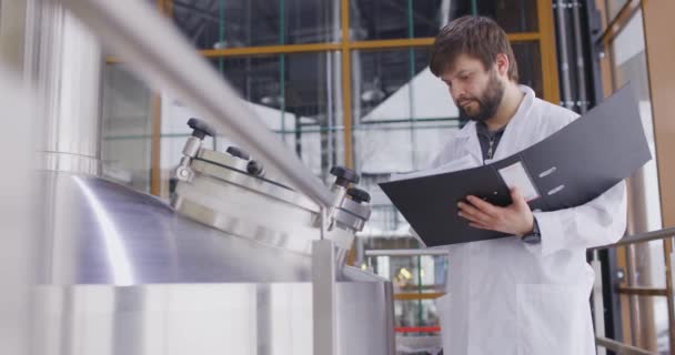 Blanke mannen die in een brouwerij of bierfabriek werken. Mannen met tablet in de buurt van de biertanks — Stockvideo