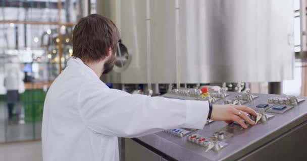 Un cervecero masculino con barba en la fábrica de cerveza que trabaja detrás del panel de control, tablero de instrumentos — Vídeo de stock