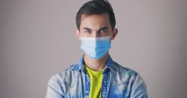 Un bell'uomo caucasico con una maschera protettiva mostra i pollici in alto, come un gesto. Una mano sola. Zoom shot — Video Stock