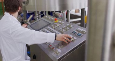 Bira fabrikasında sakallı bir erkek bira üreticisi kontrol panelinin arkasında çalışıyor.