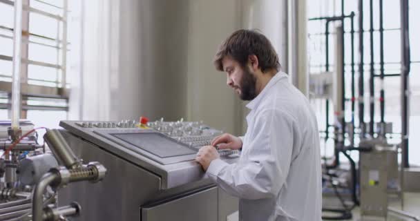 Um cervejeiro macho com uma barba na fábrica de cervejaria trabalhando atrás do painel de controle, painel — Vídeo de Stock