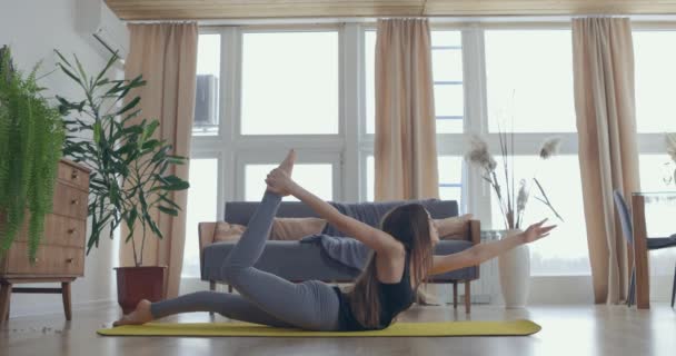 Mulher saudável e bonita se exercitando em casa praticando alongamento na sala de estar desfrutando de treino de fitness matinal. Movimento lento — Vídeo de Stock
