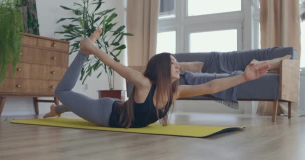 Mulher saudável e bonita se exercitando em casa praticando alongamento na sala de estar desfrutando de treino de fitness matinal. Movimento lento — Vídeo de Stock