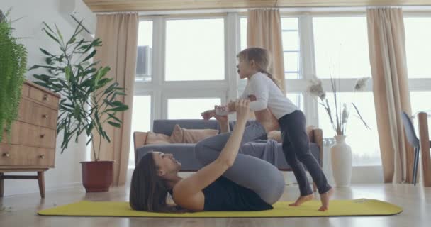 Szczęśliwa piękna rodzina zdrowa młoda mama podnoszenie słodkie dziecko córka w górę grając samolot na ścianie w domu, śmieszne dziecko dziewczyna latające w nogi matki praktyki acro para joga bonding zabawy razem — Wideo stockowe