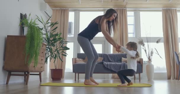 Active young mom and cute little kid daughter play on mat at living room, happy family mother with child girl having fun enjoy playing funny activity together at home — Stock Video