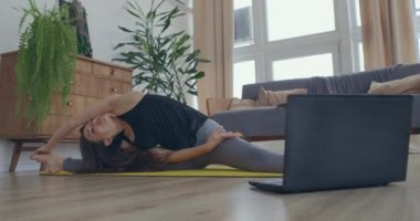 Çekici genç aktif kadın evde yoga dersleri alıyor, dizüstü bilgisayardan özel ders izliyor. Sağlıklı yaşam, sağlıklı kavramları koru.
