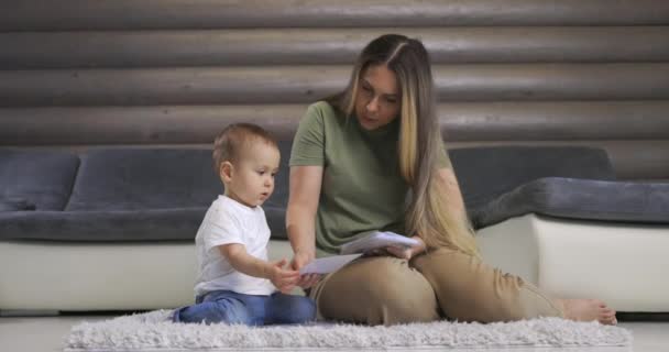 Happy young mother and baby son playing with alphabet card on warm floor at home, early education at home. — Stok Video