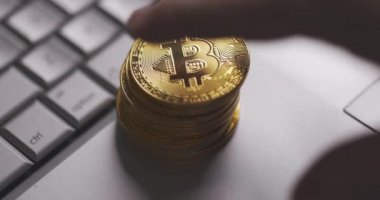 Bitcoin BTC kripto para birimi. Altın sikkeler dizüstü bilgisayarın klavyesine düşüyor. El piramidi itiyor