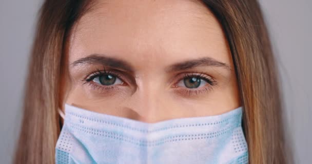 여성의 눈을 클로즈업 합니다. 의료용 마스크를 쓴 여성, 카메라를 보고 매크로 샷 — 비디오