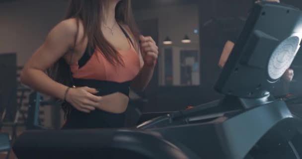 남자와 여자가 체육관에서 러닝 머신을 달립니다. 측면 운동 선수의 다리를 보고 느린 움직임 — 비디오