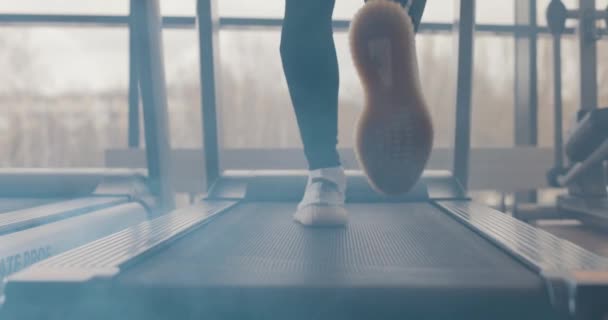Close-up atletische voeten lopen op loopband in de fitnessruimte, slow motion. Achteraanzicht van witte sneakers die trainen op de loopband. Weinig zicht op mannenbenen training in sportclub — Stockvideo
