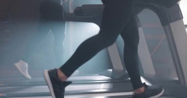 Kadın ve erkek spor salonunda koşu bandında koşuyorlar. Atletik insanların bakış açısının altında, yavaş çekim