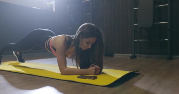 Aantrekkelijke fitness vrouw doet plank oefening workout op mat in de sportschool, slow motion — Stockvideo