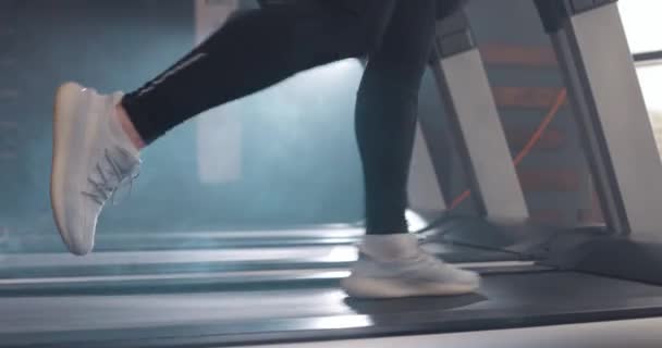 Close-up atletische voeten lopen op loopband in de fitnessruimte, slow motion. Zijaanzicht van witte sneakers met workout op loopband. Weinig zicht op mannenbenen training in sportclub — Stockvideo