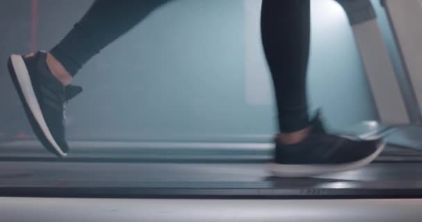 Vue rapprochée des jambes féminines en baskets courant sur tapis roulant au gymnase, au ralenti — Video