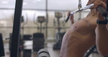 Spor salonunda halterle egzersiz yapan atletik tişörtsüz genç bir sporcu. Yakışıklı adamlar kaslarını şişiriyor. Yavaş çekim