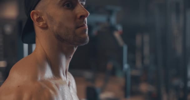 Guapo fuerte atlético hombres caucásicos bombeando los músculos del bíceps con bar en el gimnasio, ejercicio físico y el concepto de culturismo. Cámara lenta, vista lateral — Vídeo de stock