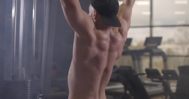 Sportovní mladík bez trička, který cvičí s činkou v tělocvičně. Pohlední muži pumpují biceps svaly. Zpomalený pohyb — Stock video