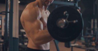 Yakışıklı, beyaz tenli, kaslı, spor salonunda bar, spor salonu ve vücut geliştirme konseptiyle kaslarını şişiren atletik erkekler. Yavaş çekim, yan görünüm