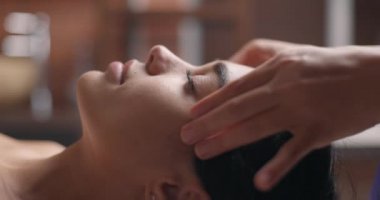 Genç ve çekici esmer kadın güzellik salonunda yüz masajı yaptırıyor. Sağlıklı yaşam tarzı ve vücut bakımı kavramı. Yavaş çekim