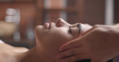 Genç ve çekici esmer kadın güzellik salonunda yüz masajı yaptırıyor. Sağlıklı yaşam tarzı ve vücut bakımı kavramı. Yavaş çekim, yakın çekim.