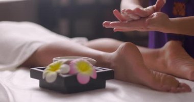 Masör kremi eline aldı. Genç ve güzel bir kadın kaplıcada ayak masajı terapisi görüyor. Yavaş çekim