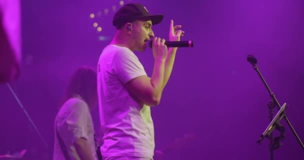 Side view portrait of a man singing to microphone on light background. Stylish cool guy performing concert on stage. Slow motion. Music and concert concept. — Stock Video