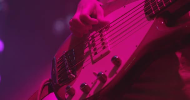 A woman is playing guitar on stage. Young woman playing on electric bass guitar. Artist Guitarist hand close-up. Slow motion — Αρχείο Βίντεο