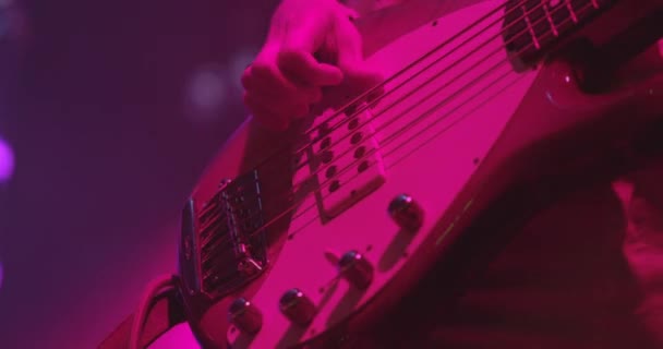 Uma mulher está a tocar guitarra no palco. Jovem tocando baixo elétrico. Artista guitarrista mão close-up. Movimento lento — Vídeo de Stock