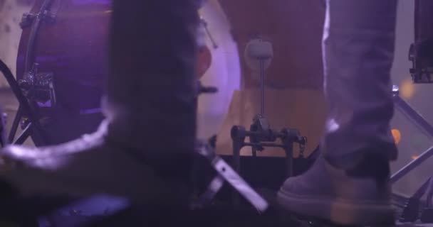 Close-up of the legs of a drummer in sneakers on stage. The drummer kicks the bass drum pedal. A man plays the drums in a musical group, live performance. Slow motion — Stock Video