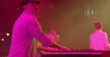 Man Musician 'ın arka planı konserde Sentezleyici' yi çalıyor. Parlak Sahne Işığı. Arka planda kadın vokalist. Yavaş çekim.
