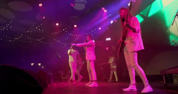 Concert music band performing on stage with singer. Music video punk, pop or rock group. Stage neon light, smoke, slow motion — Stock Video