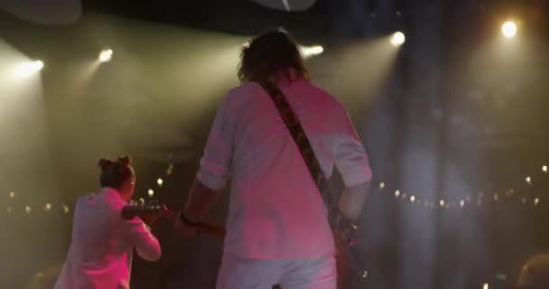 Blick zurück Gitarrist bei einem Rockkonzert spielt E-Gitarre auf der Bühne. Sängerin im Hintergrund. Zeitlupe — Stockvideo
