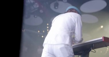 Man Musician 'ın arka planı konserde Sentezleyici' yi çalıyor. Parlak Sahne Işığı. Arka planda kadın vokalist. Yavaş çekim.