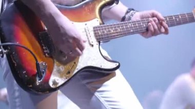 Gitarist rock müzik çalar. Canlı bir konserde duygusal ve dinamik bir performans. Parlak sahne ışığı. Yakın plan.
