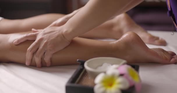 Frau entspannt sich und lässt sich von einer Therapeutin auf die Beine massieren. Dolly Shot professionelle Behandlung im Wellness-Spa. Konzept der Körperpflege. Zeitlupe. — Stockvideo