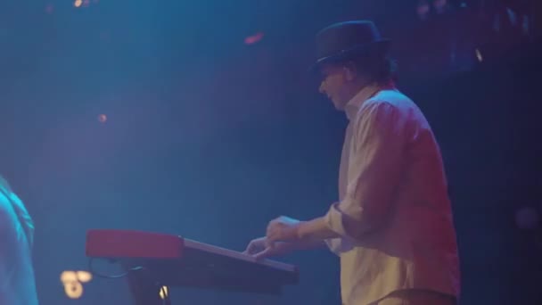 Back view of Man Musician Plays The Synthesizer At The Concert. Bright Stage Light. Woman Vocalist At Background. — Stock Video