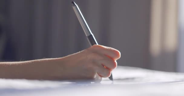 Крупним планом перегляд жіночої руки за допомогою цифрового планшетного малюнка зі стилусовою ручкою. Дизайнер, що працює на ліжку вдома . — стокове відео