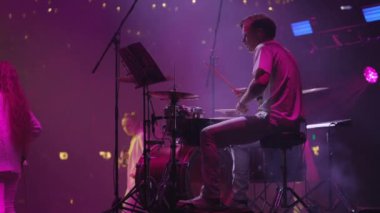 Parlak neon ışıklara karşı müzik aleti çalan müzisyen. Pop grubunun canlı konseri sahnede.