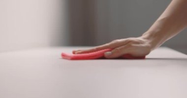 Kadın eli, masa yüzeyini pembe bir bezle temizliyor. Yavaş çekim