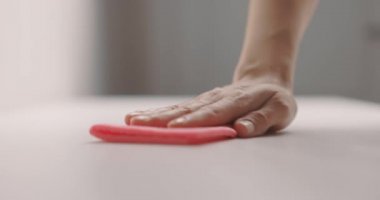 Kadın eli, masa yüzeyini pembe bir bezle temizliyor. Yavaş çekim