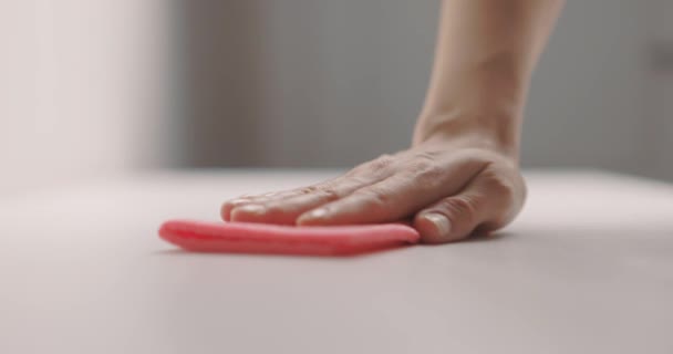 La mano femenina limpia la superficie de la mesa con un trapo rosa. Movimiento lento — Vídeos de Stock